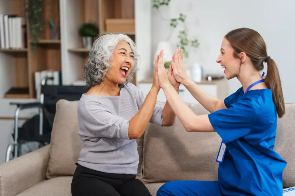A joyful Careline 24 carer and an elderly client share a celebratory high-five, highlighting a positive achievement and the genuine, uplifting relationship they share.