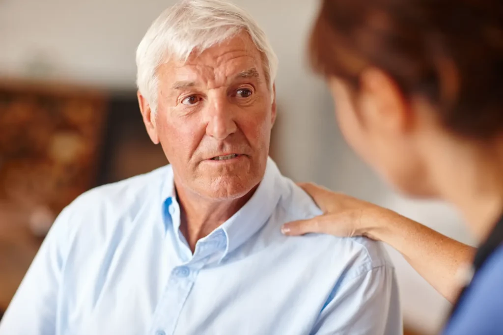 A compassionate Careline 24 carer gently checking on the wellbeing of an elderly lady during a home visit, showing genuine care and attention.