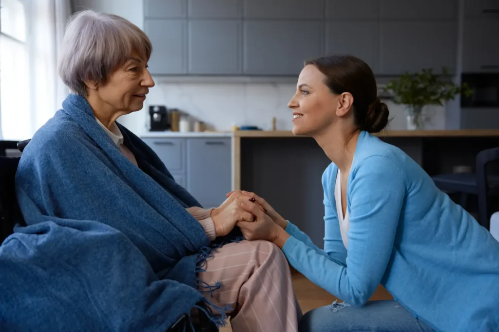  A compassionate Careline 24 carer in Chichester holds the hands of an elderly client, offering reassuring support and companionship in their own home.