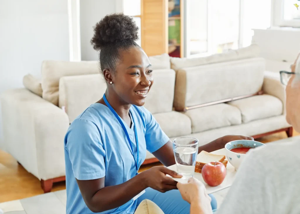 A professional carer and an elderly client work together to prepare a healthy, home-cooked meal in her kitchen.
