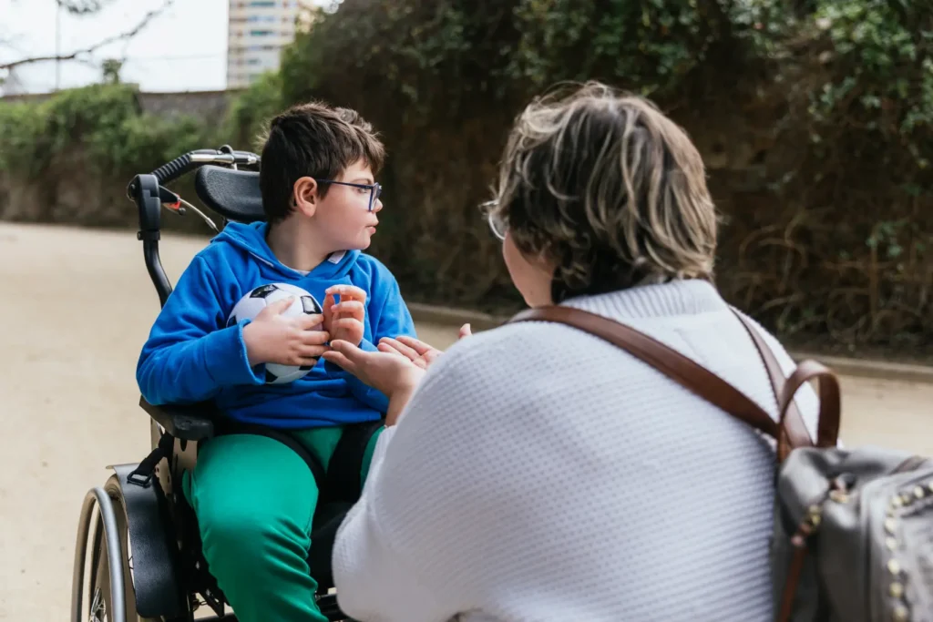 A happy child with a learning disability and their dedicated carer from Careline 24 enjoying time together in a sunny garden, holding a freshly picked tomato.