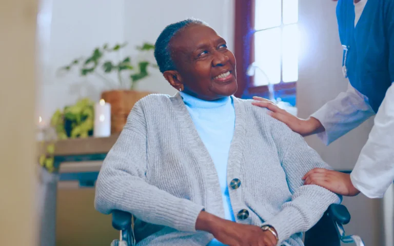 older woman in a wheelchair smiles warmly at her carer