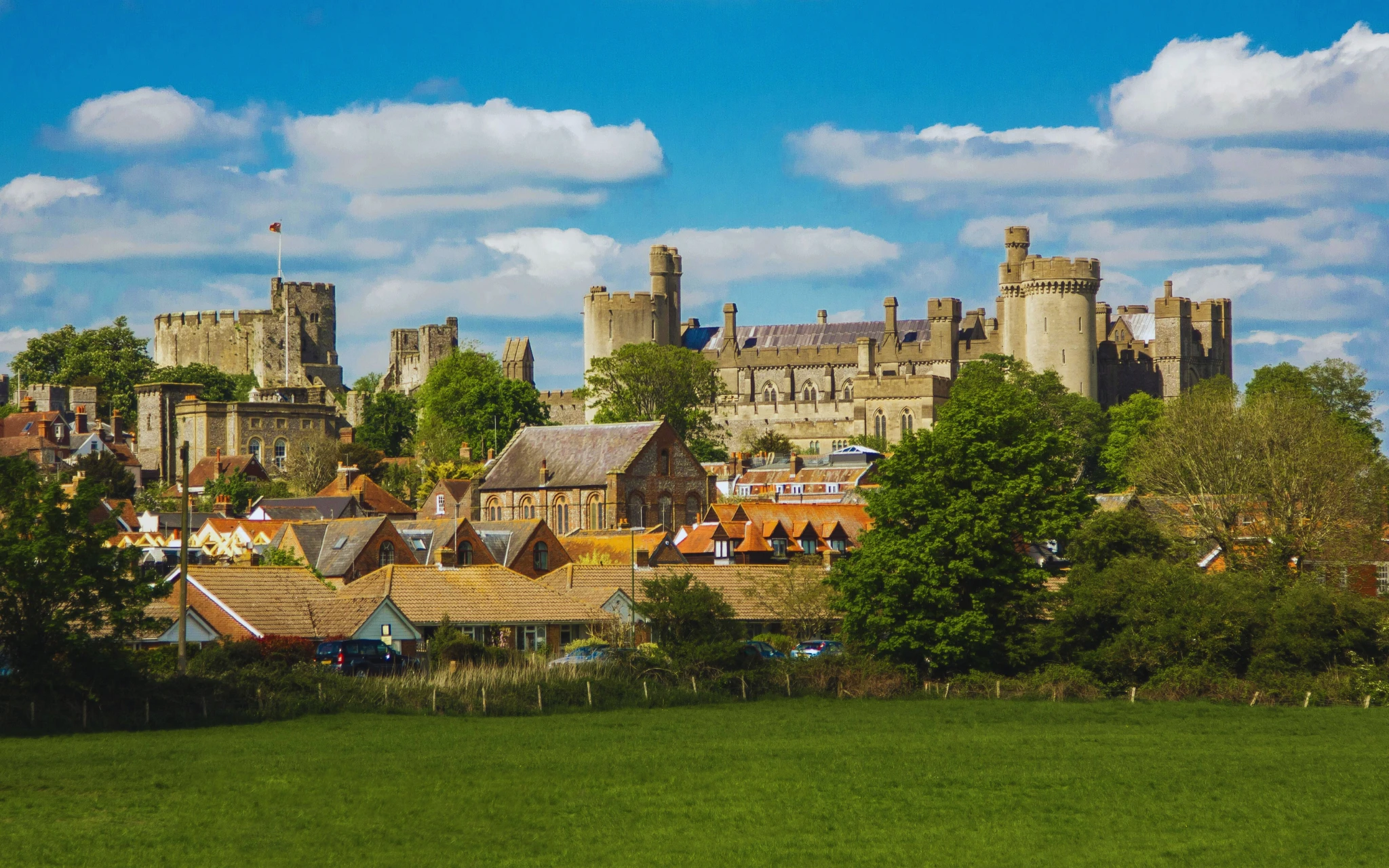 Landscape view of Arundel Castle surrounded by trees, historic buildings, and open green countryside in West Sussex.