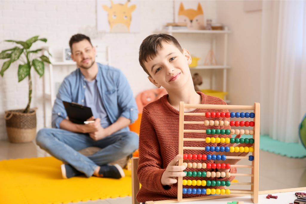 A caring support worker from Careline 24 engaging in a calm, focused activity with a young autistic boy in the comfortable and familiar setting of his own home.