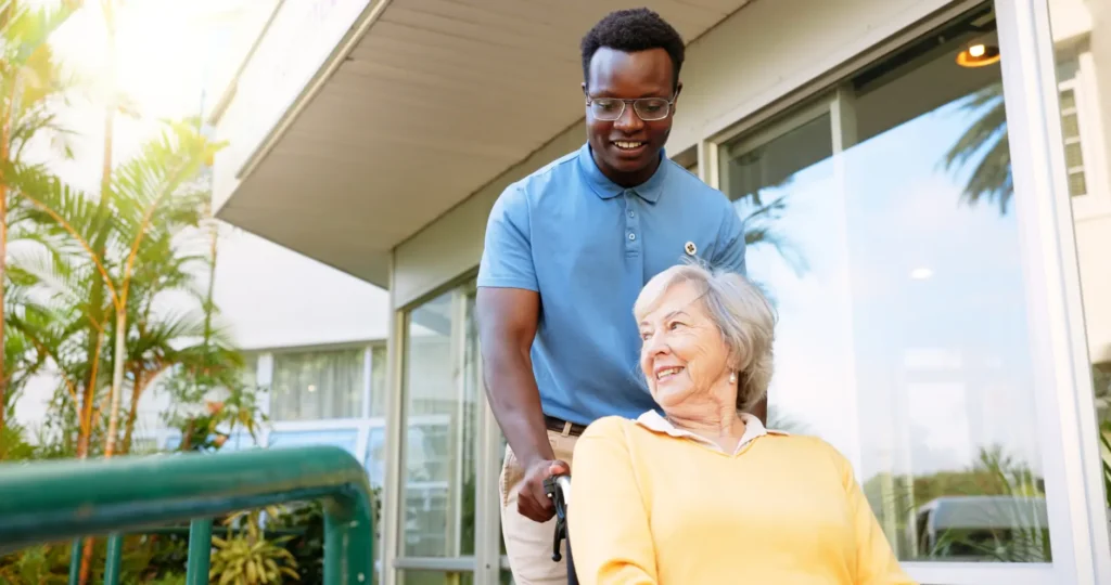 A compassionate live-in carer provides supportive mobility assistance to an elderly lady using a wheelchair in her home, promoting her independence and safety.