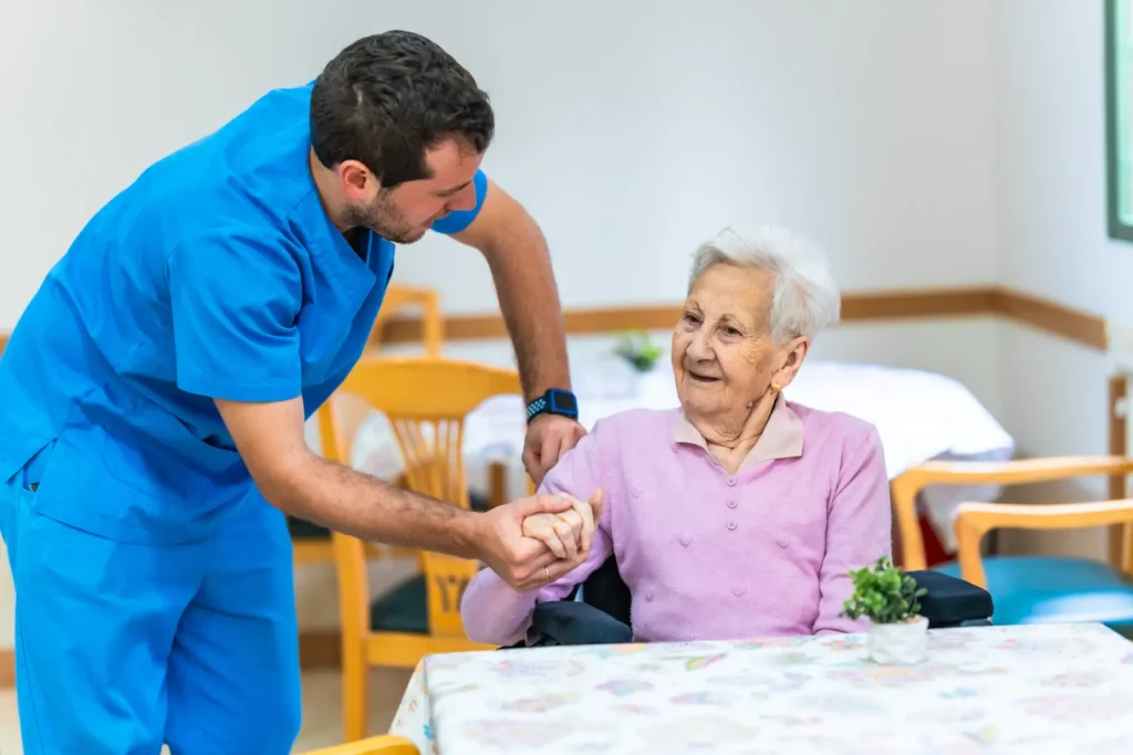 Male carer gently assisting an elderly woman, offering professional and compassionate support in a safe home care setting.