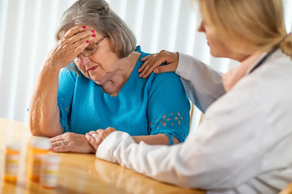 A compassionate Careline 24 mental health carer providing emotional support and reassurance to an elderly woman during a difficult moment in her home.