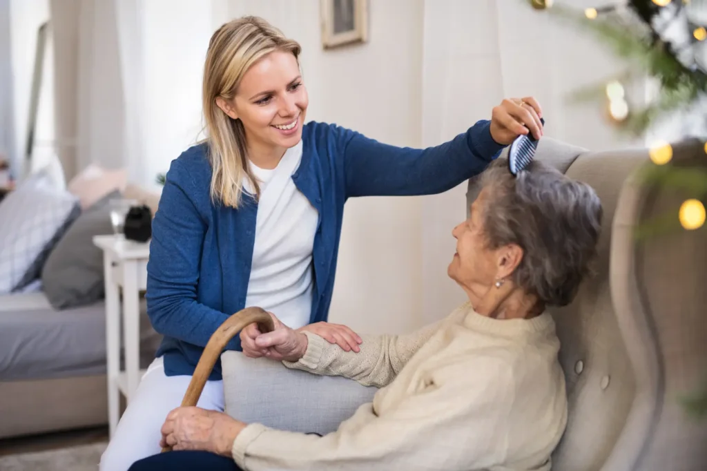 A compassionate Careline 24 carer provides gentle, dignified personal care by brushing the hair of a senior woman in her Chichester home.