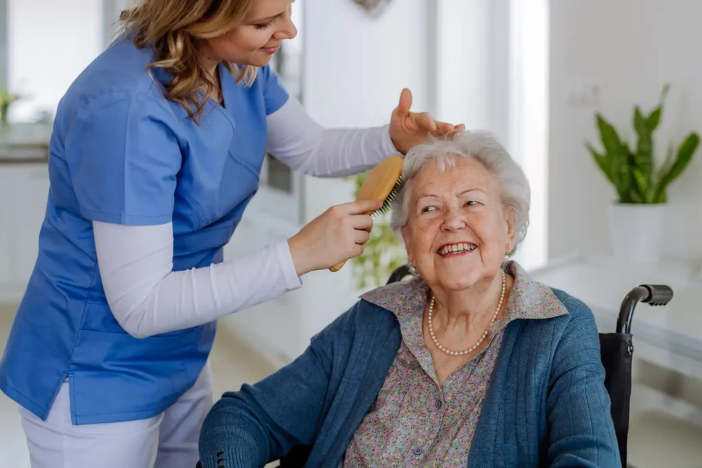A compassionate Careline 24 carer styles the hair of her senior client with dignity and care in their Littlehampton home, providing gentle personal care support.