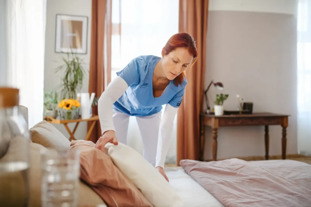 A professional carer from our consistent team provides light household support by making the bed for a client during a home care visit.