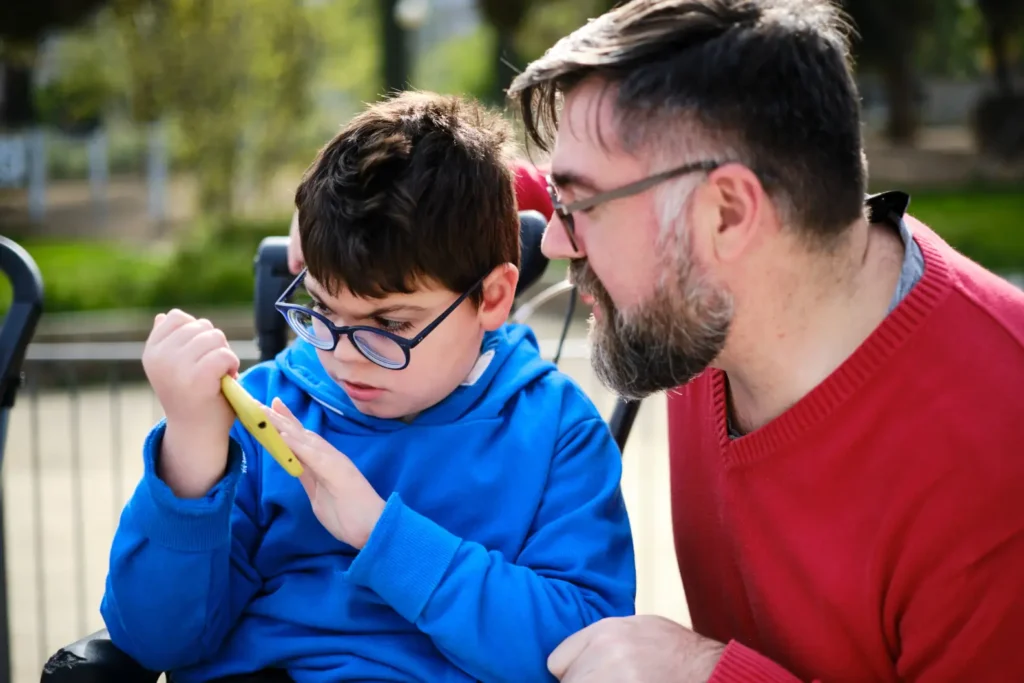 A smiling young adult with a learning disability uses a smartphone confidently at home, showcasing independence and modern connection.